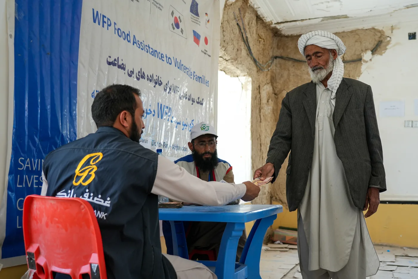 An older man meets staff at a WFP food assistance registration desk